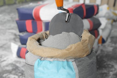 Photo of Cement powder and trowel put in bag indoors, closeup