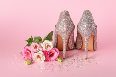 Stylish women's high heeled shoes and beautiful flowers on pink background
