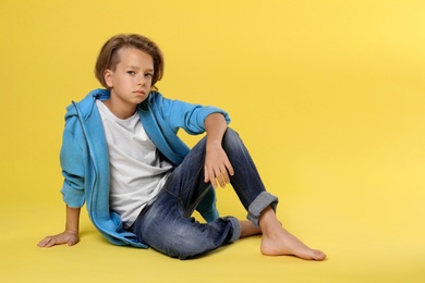 Cute little boy in casual outfit on yellow background. Space for text