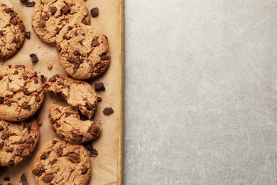 Photo of Delicious chocolate chip cookies on parchment paper, top view. Space for text