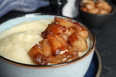 Photo of Potato puree and tasty fried cracklings on table, closeup. Cooked pork lard