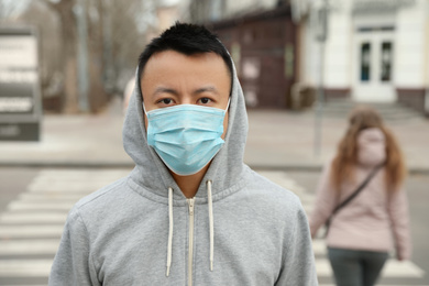 Asian man wearing medical mask on city street. Virus outbreak