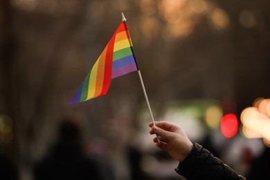 Woman holding small LGBT flag on city street, closeup