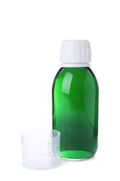 Photo of Bottle of syrup with measuring cup on white background. Cough and cold medicine