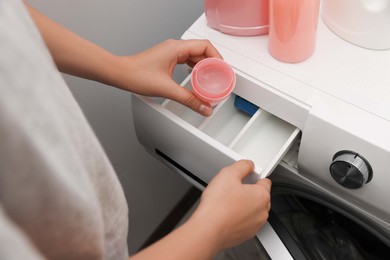 Woman pouring laundry detergent into drawer of washing machine, closeup