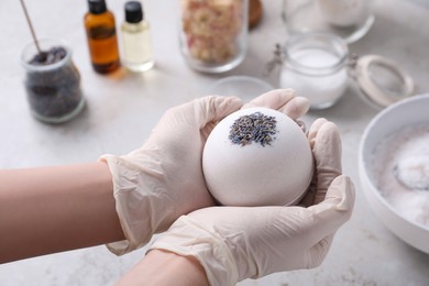 Woman in gloves with self made bath bomb at grey table, closeup