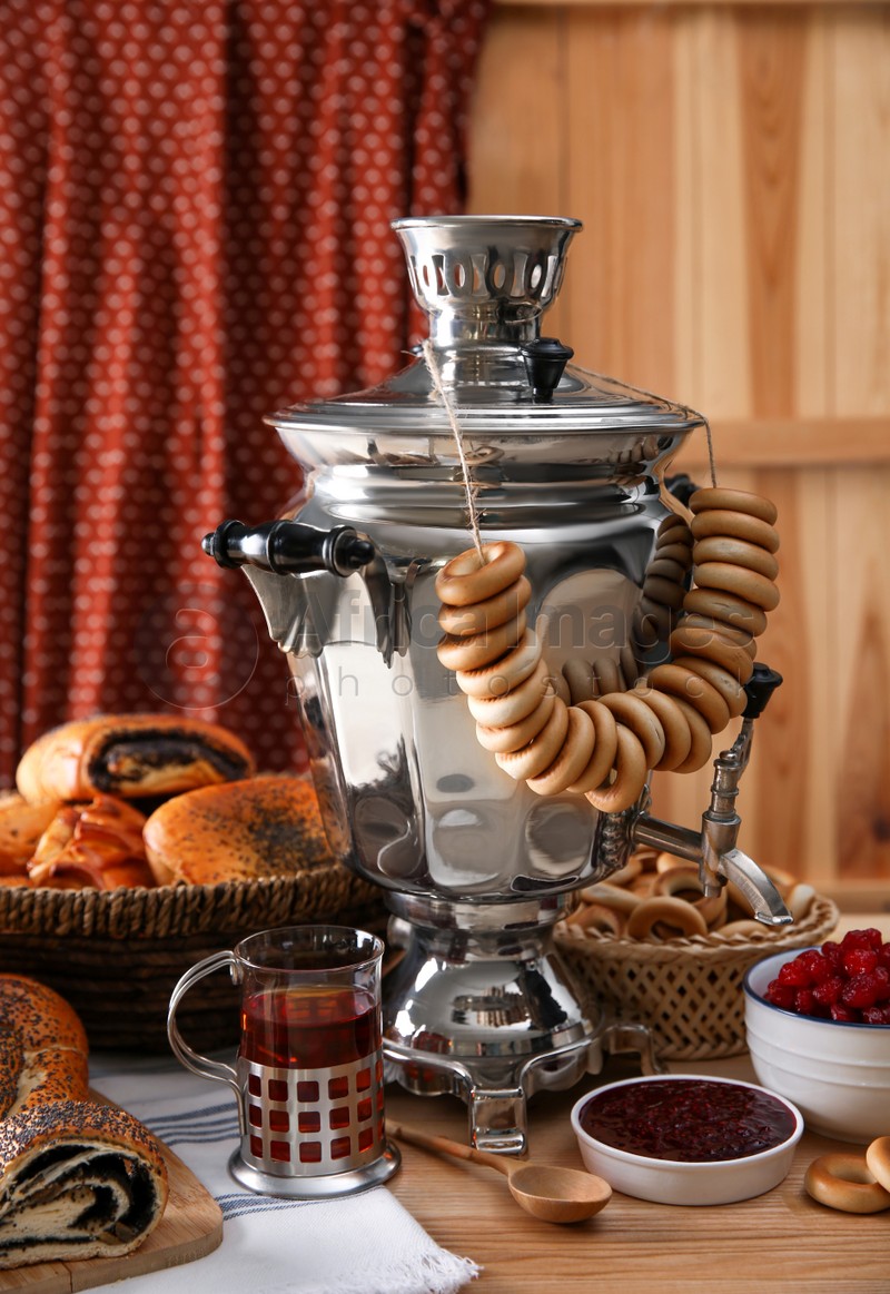 Photo of Traditional Russian samovar and treats on wooden table