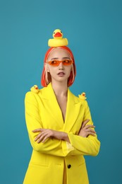 Photo of Beautiful young woman with bright dyed hair and toy ducks on turquoise background
