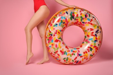 Young woman with inflatable ring against pink background, closeup