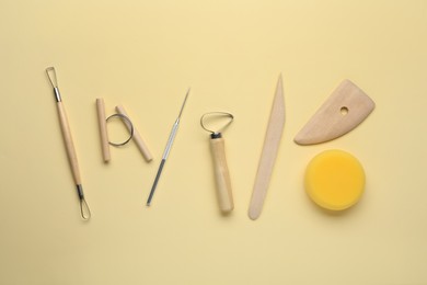 Photo of Set of clay modeling tools on beige background, flat lay