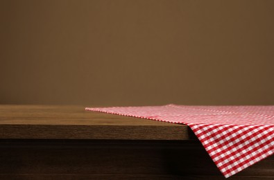 Red and white checkered tablecloth on wooden desk, space for design