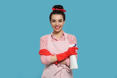 Young housewife with detergent on light blue background