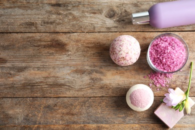 Photo of Flat lay composition with bath bombs, toiletries and space for text on wooden background