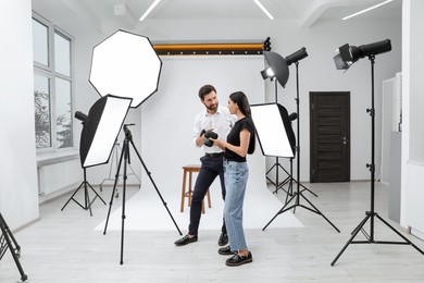 Photo of Professional photographer and model looking at pictures on camera in modern studio