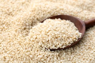 Wooden spoon on pile of white sesame seeds, closeup
