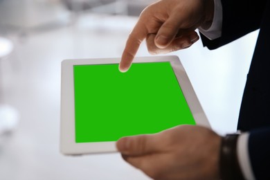 Image of Businessman using digital tablet indoors, closeup. Device display with chroma key