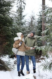 Couple in conifer forest on snowy day. Winter vacation