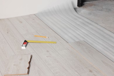 Photo of Ruler, pencil and parquet plank on laminated flooring indoors
