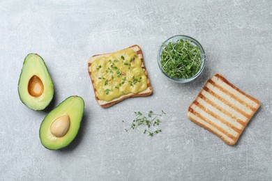 Delicious sandwich with guacamole and microgreens on grey table, flat lay