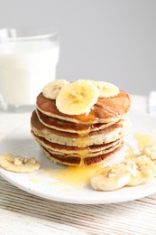 Plate of banana pancakes with honey on white wooden table