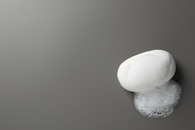 Soap with fluffy foam on grey background, top view. Space for text