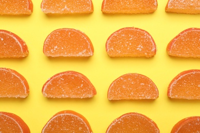 Delicious orange marmalade candies on yellow background, flat lay