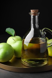 Photo of Fresh ripe green apples and jug of tasty juice on black table, closeup