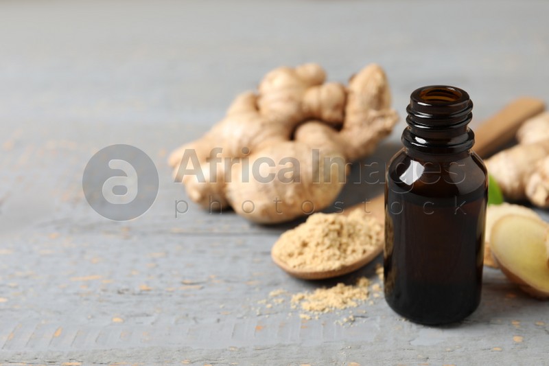 Photo of Ginger essential oil in bottle on light grey table. Space for text
