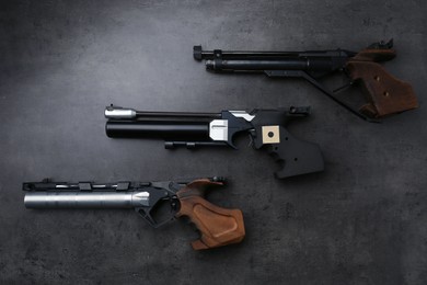 Many different sport pistols on black table, flat lay. Professional guns