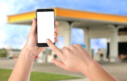 Man paying for refueling via smartphone at gas station, closeup. Device with empty screen