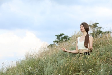Photo of Teenage girl meditating on hill. Space for text