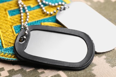 Military ID tags and Ukrainian patch on pixel camouflage, closeup