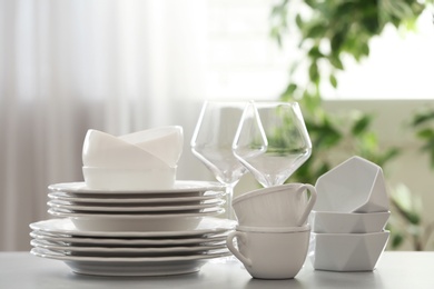 Photo of Set of clean dishware and wineglasses on table indoors