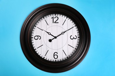 Stylish wall clock on turquoise background, top view