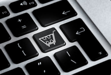Modern laptop keyboard with cart symbol, closeup view. Internet shopping