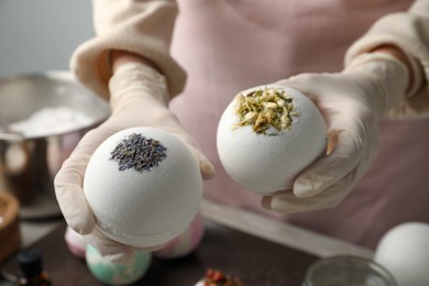 Woman in gloves with self made bath bombs at table, closeup
