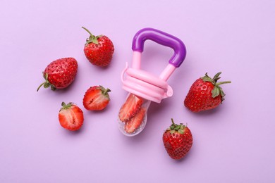 Nibbler with fresh strawberries on violet background, flat lay. Baby feeder