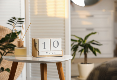 Wooden block calendar and aromatic reed air freshener on white table indoors. Space for text