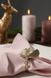 Pink fabric napkin with beautiful decorative ring for table setting on plate, closeup