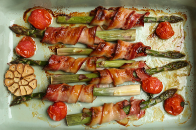 Oven baked asparagus wrapped with bacon in ceramic dish, top view