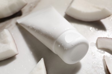 Tube of hand cream and coconut pieces on wet marble table, closeup