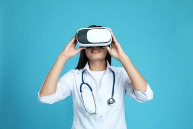Female doctor using virtual reality headset on light blue background