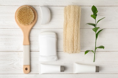 Flat lay composition with natural deodorant and bath accessories on white wooden table