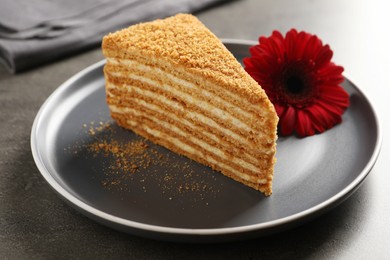 Slice of delicious layered honey cake served on grey table, closeup