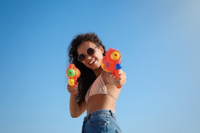 African American woman with water guns having fun against blue sky