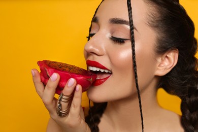 Photo of Young woman with fresh pitahaya on yellow background, closeup. Exotic fruit