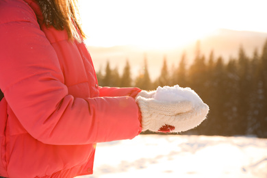 Woman holding pile of snow outdoors, closeup. Winter vacation