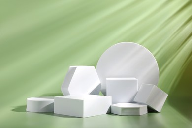 Product photography props. Podiums of different geometric shapes on light pale green background
