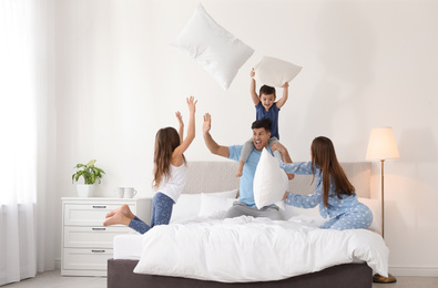 Happy family having pillow fight in bedroom