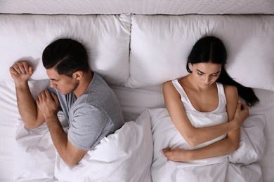 Unhappy couple with relationship problems after quarrel in bed, top view